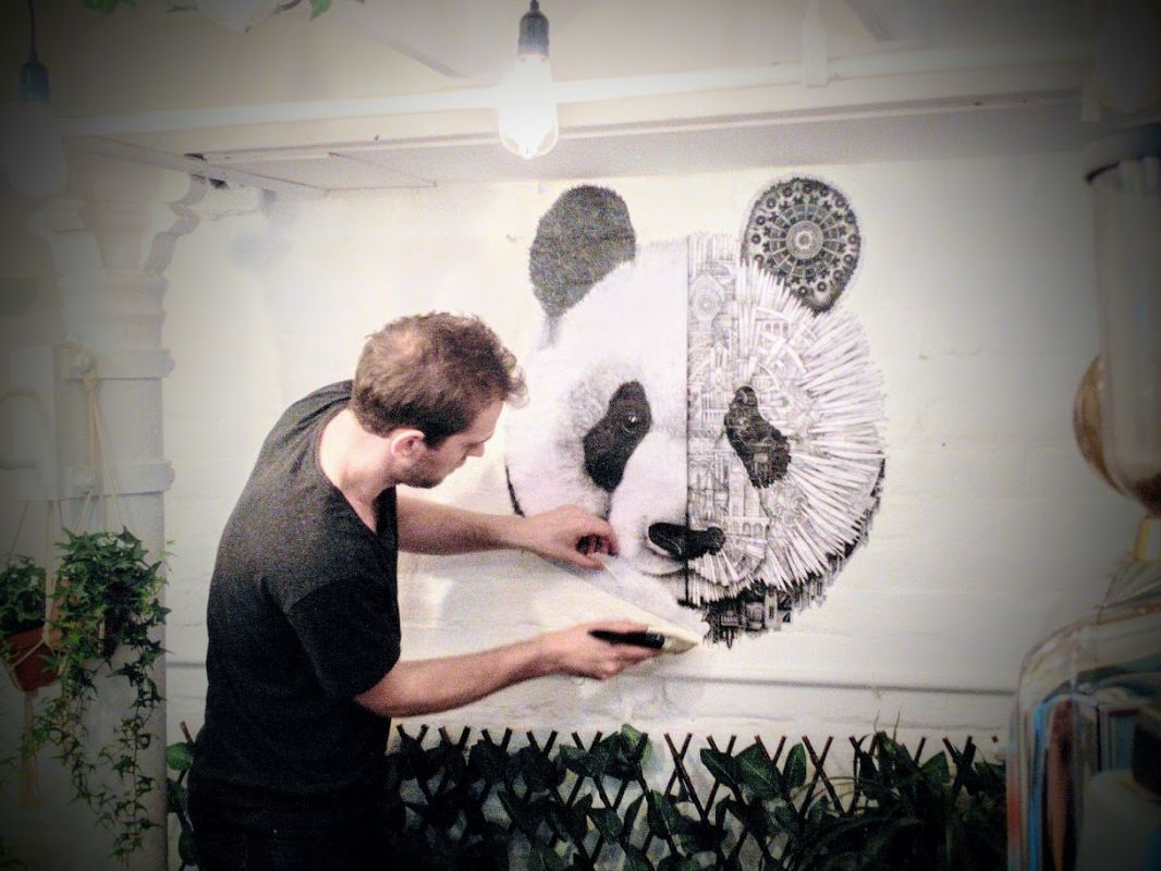 French artist Ardif installing a paste-up at Long and Short coffee shop in Brick Lane